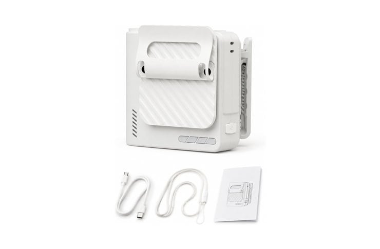 Small white compact printer with a roll-fed media path, plus USB cables and a quick-start manual beside it.