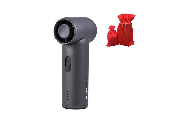 Cordless handheld percussion massage device with cylindrical head, brand Docotair shown beside two red gift bags